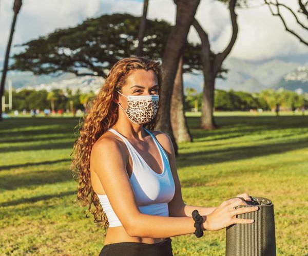 Smiling woman stretching gently on a yoga mat in a bright room.